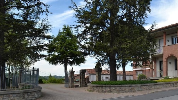 A two-story building with a balcony, a stone entrance, and a paved driveway. - Residence la Quiete (Guarene)