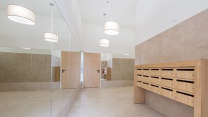 A modern, well-lit hallway with a wooden storage unit and glass partitions.