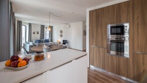 A modern kitchen with a built-in microwave and oven, a dining area with a table and chairs, and a fruit bowl on the counter.