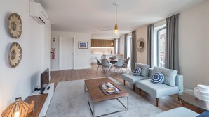 A modern living room with a sofa, coffee table, and a dining area in the background.