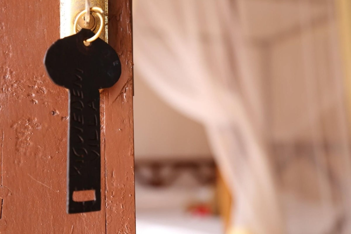 A keyhole with a key inserted, a wooden door, and a blurred background suggesting an indoor setting.