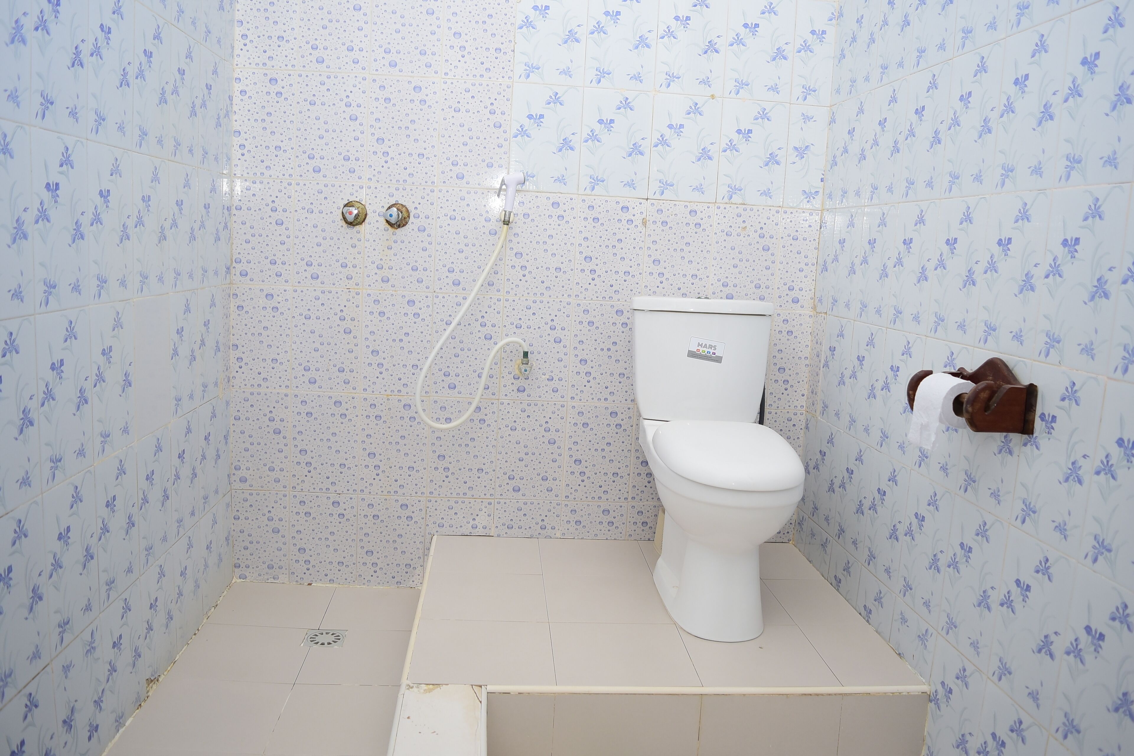 A bathroom with a toilet, a shower, and a towel dispenser.