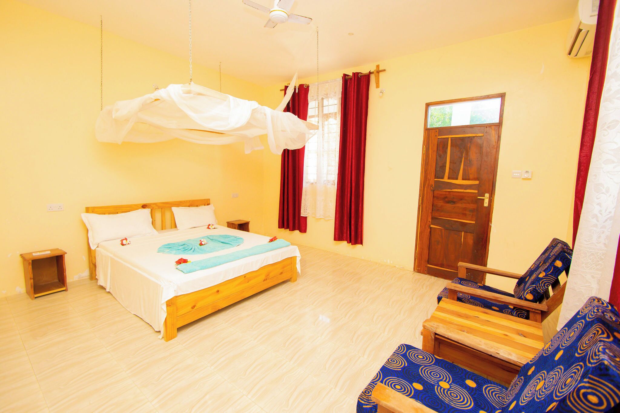 A bedroom with a bed, a wooden chair, a small table, and a door.