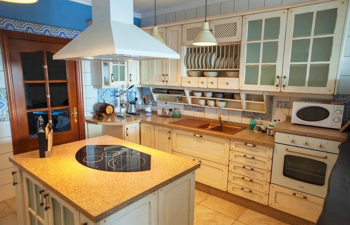 Una cocina con estufa, microondas, horno y diversos utensilios.