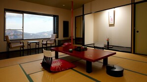 A traditional Japanese room with tatami flooring, a low table, and a view of mountains through large windows. - ikaho shinki (Shibukawa)