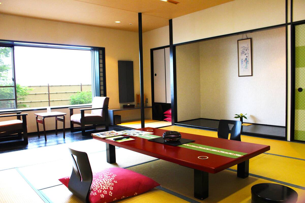 A traditional Japanese room with tatami flooring, a low table with cushions, and sliding doors.