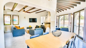 A spacious living area with a wooden ceiling, a fireplace, and a dining table with chairs. - Villa with pool and garden Don Quijote AM 6 Pers Denia (Denia)
