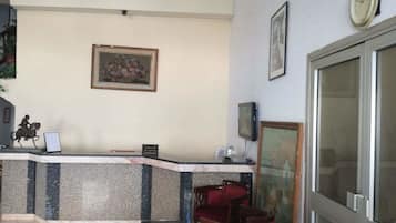Un espace d’accueil doté d’un comptoir en marbre, de tableaux encadrés, d’une horloge et d’un téléviseur.