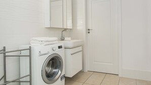 Une salle de bain moderne et compacte, équipée d’un lave-linge, d’un lavabo et d’un miroir.