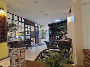An indoor seating area with tables and chairs, a menu stand, and a view of the street outside. - Tamarind Hotel Da Nang (Da Nang)