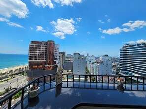 A balcony with a view of a beach and cityscape, including a hotel with a sign 'AVATAR DANANO'. - Tamarind Hotel Da Nang (Da Nang)