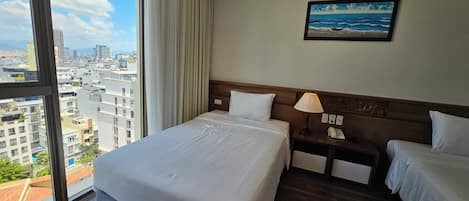 A hotel room with a large bed, a bedside table with a lamp, a phone, and a painting of a beach scene.