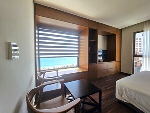 A hotel room with a bed, a desk, a chair, a TV, and a window with a view of the beach. - Tamarind Hotel Da Nang (Da Nang)
