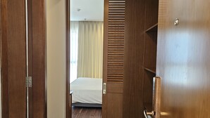 A hotel room with a wooden door, a bed with white bedding, and a window with curtains. - Tamarind Hotel Da Nang (Da Nang)