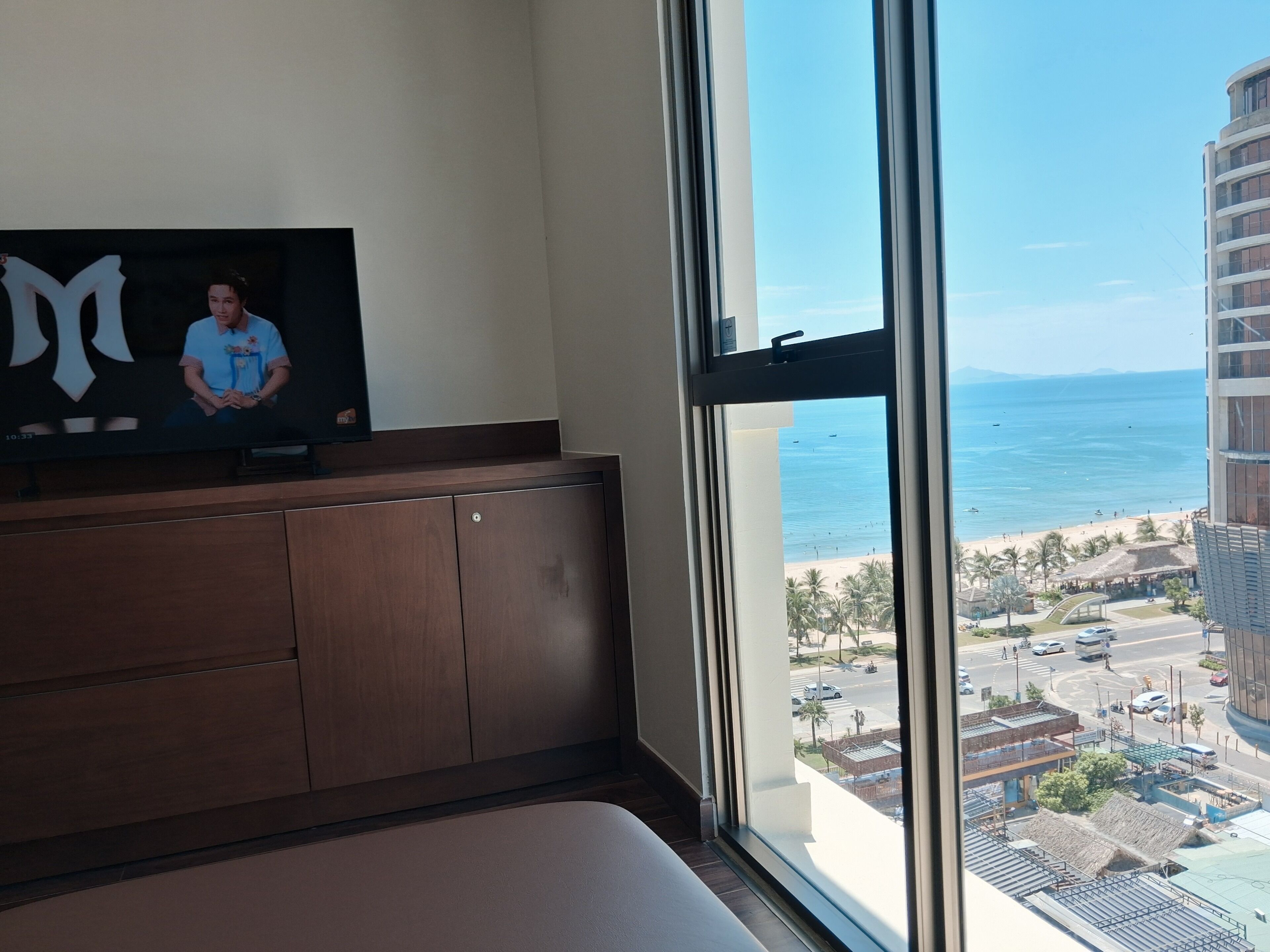A room with a large window overlooking a beach and a cityscape.