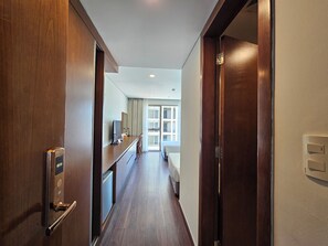 A hotel corridor with wooden doors, a minibar, and a view into a room with a bed and curtains. - Tamarind Hotel Da Nang (Da Nang)