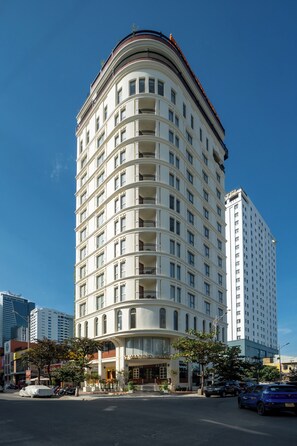 Un hotel de varios pisos con fachada curva, balcones y una entrada destacada.