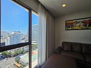 A room with a large window, a sofa, and a painting on the wall. - Tamarind Hotel Da Nang (Da Nang)