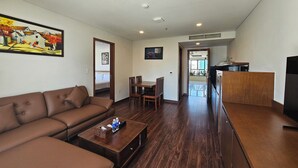A modern living room with a brown leather sofa, a wooden coffee table, and a dining area with wooden chairs. - Tamarind Hotel Da Nang (Da Nang)