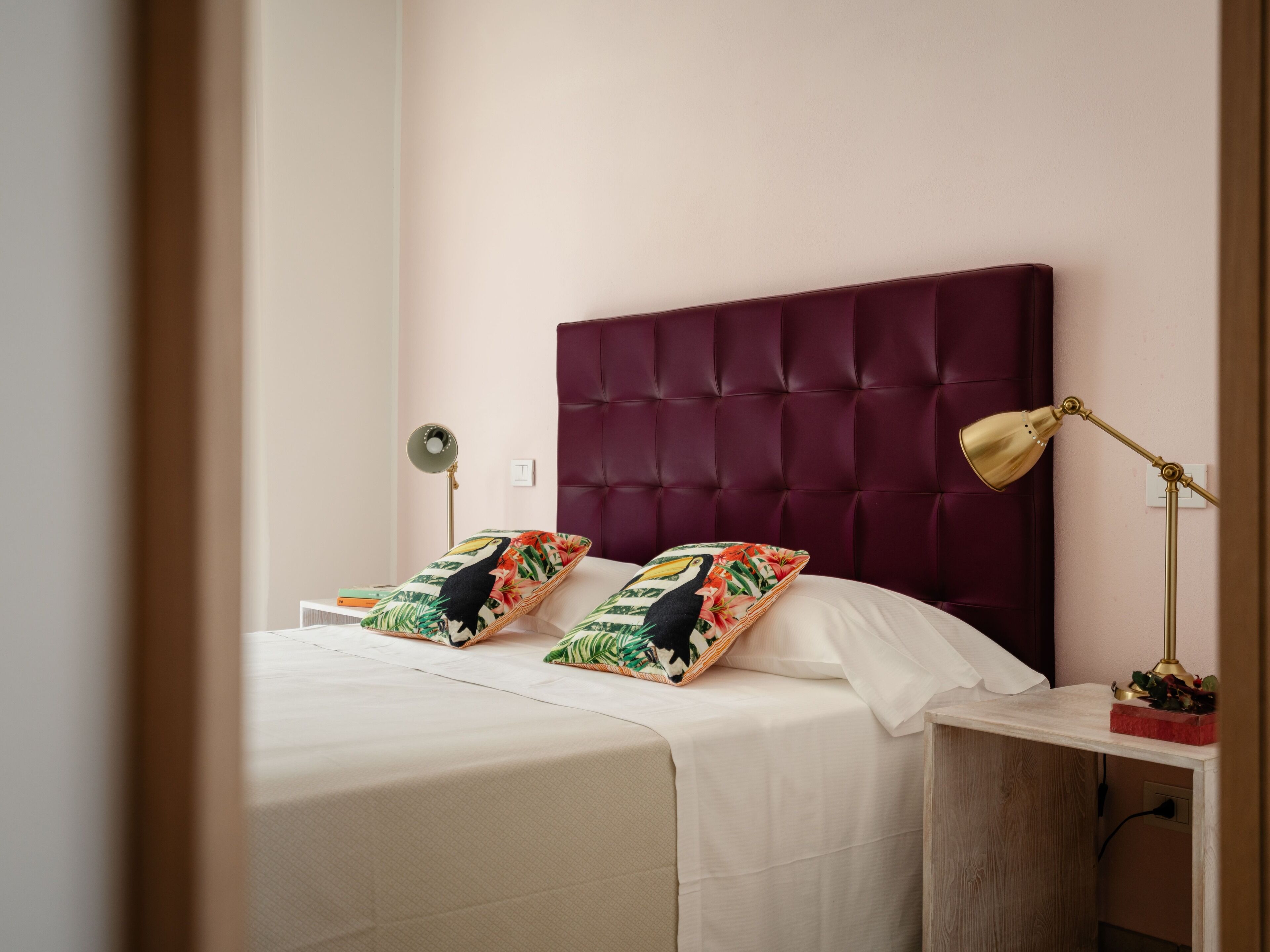 Un letto rifatto con due cuscini, una lampada da comodino e un tavolino con una pianta.