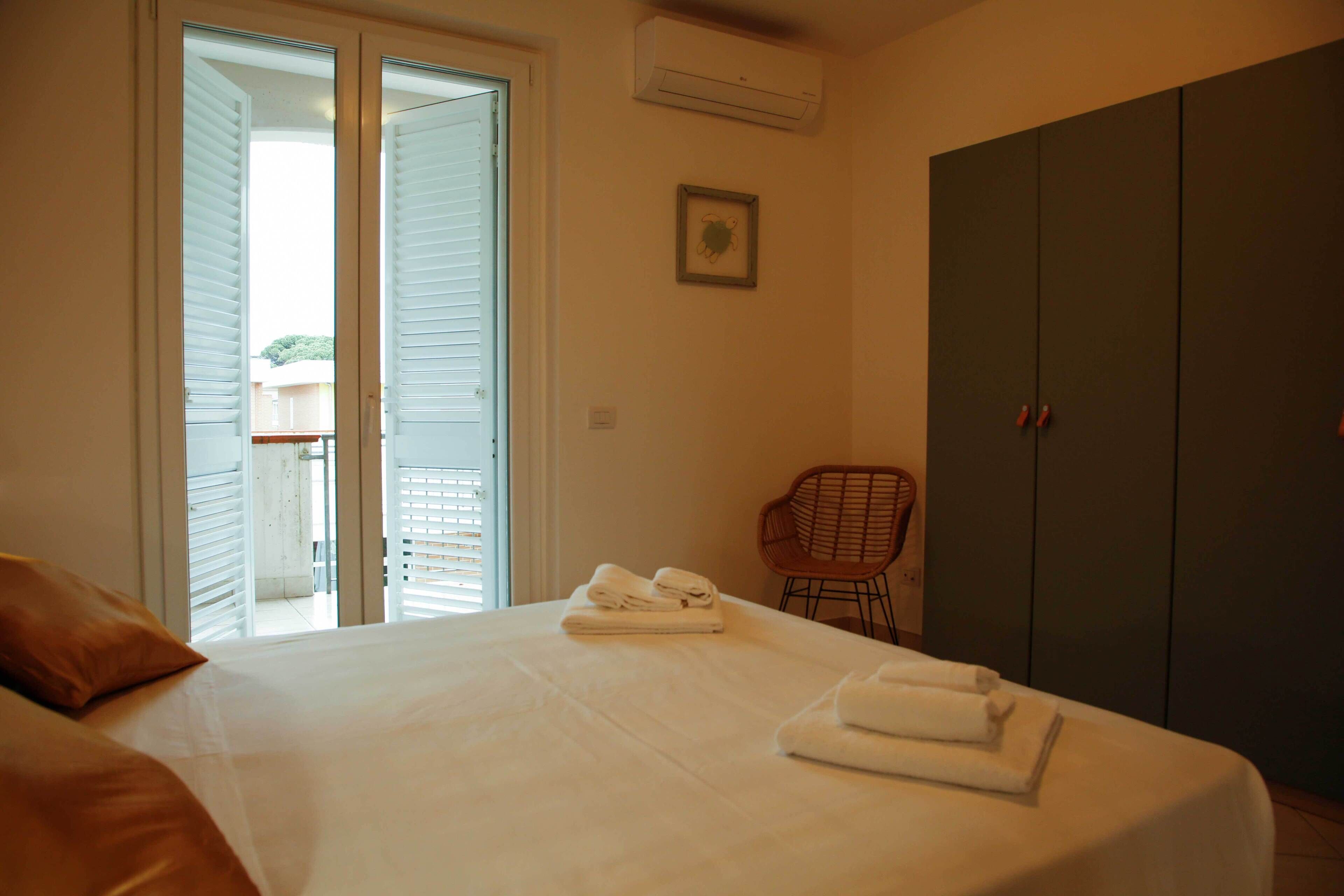 Une chambre à coucher comprenant un lit, une chaise, une armoire et une porte donnant sur un balcon.