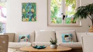 A modern living room with a white sofa, a round wooden coffee table, and a large window with a view of greenery. - I Cinque Pini (Follonica)