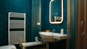 Een badkamer met een wit toilet, een witte wastafel met spiegel en een handdoekrek.