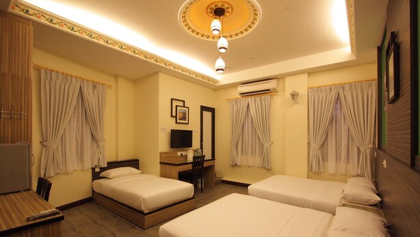A hotel room with two beds, a desk, a chair, a television, and an air conditioning unit. - Shamrock Guest House II (Ipoh)