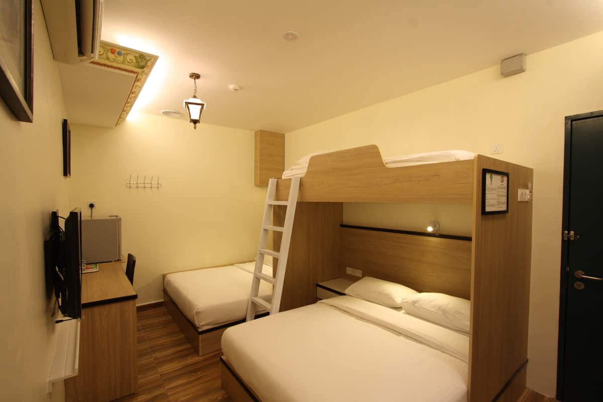 A compact hotel room with bunk beds, a desk with a computer, and a small TV.