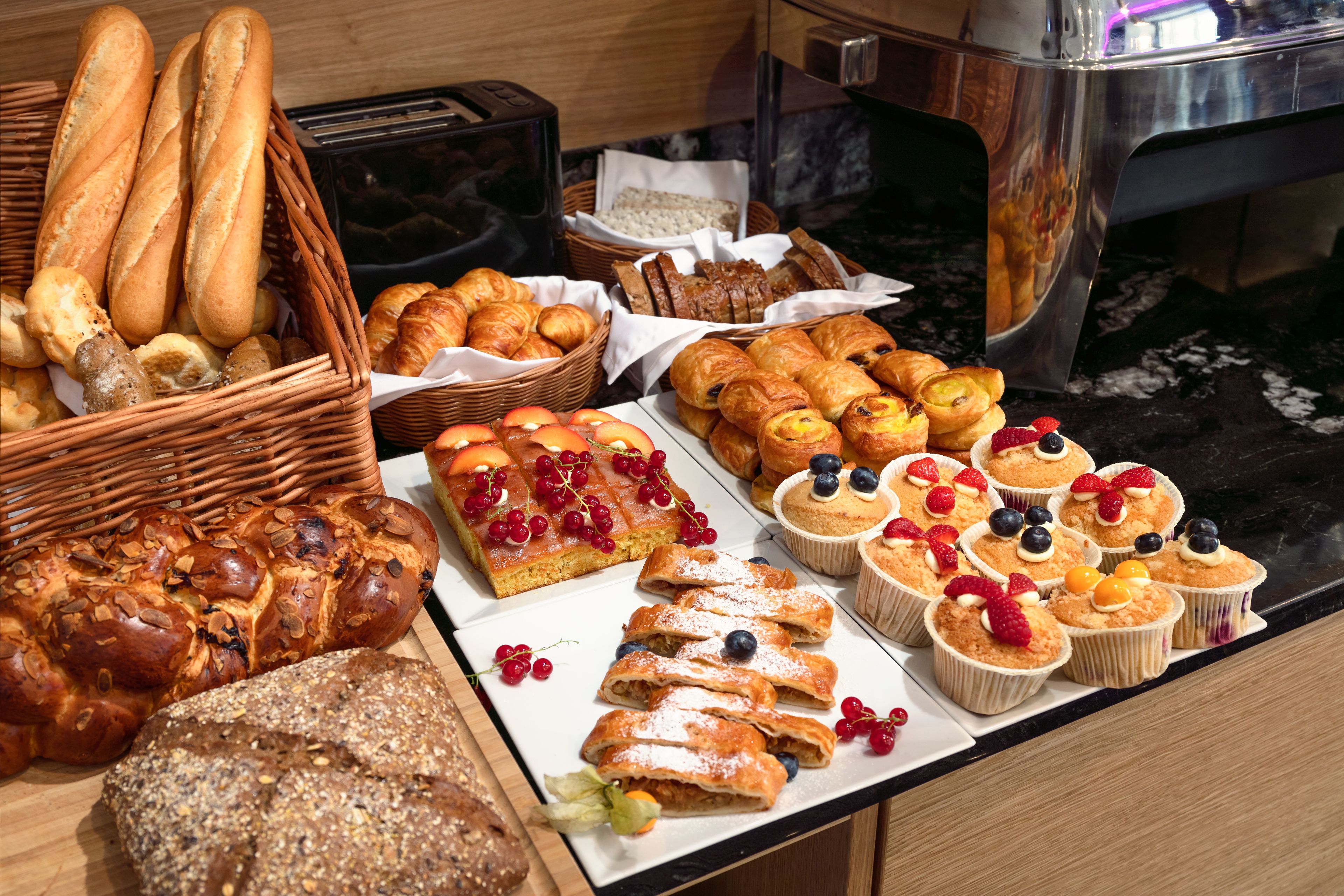 Un buffet proposant une variété de pains, de pâtisseries et de desserts garnis de fruits.