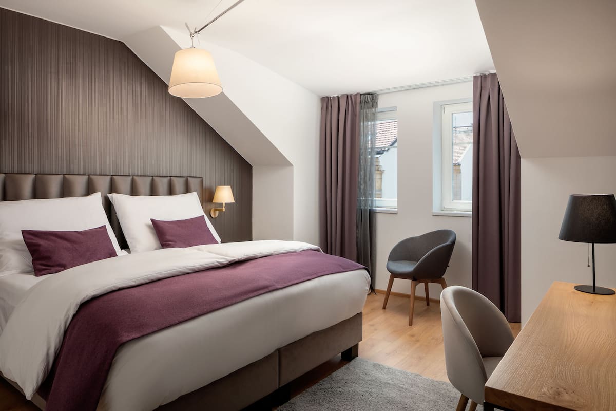 A modern bedroom with a large bed, a desk, and a chair.
