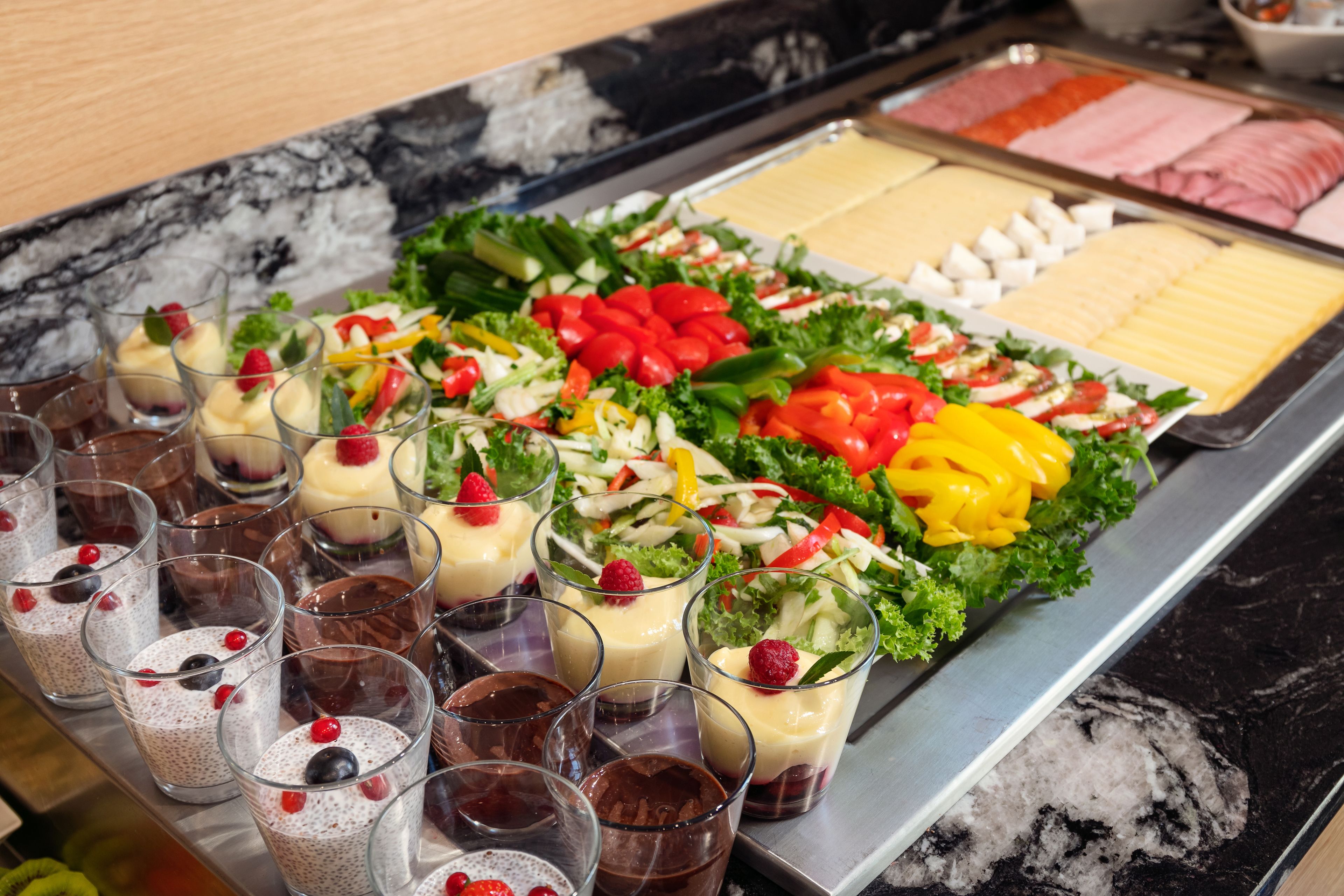 A buffet with various food options including salads, cheeses, and desserts.
