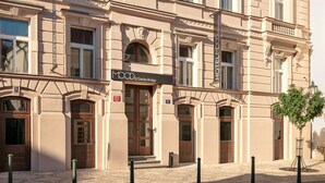 Un hôtel à plusieurs étages, de style architectural classique, qui se distingue par son entrée imposante, avec une grande porte en bois et une enseigne au-dessus.