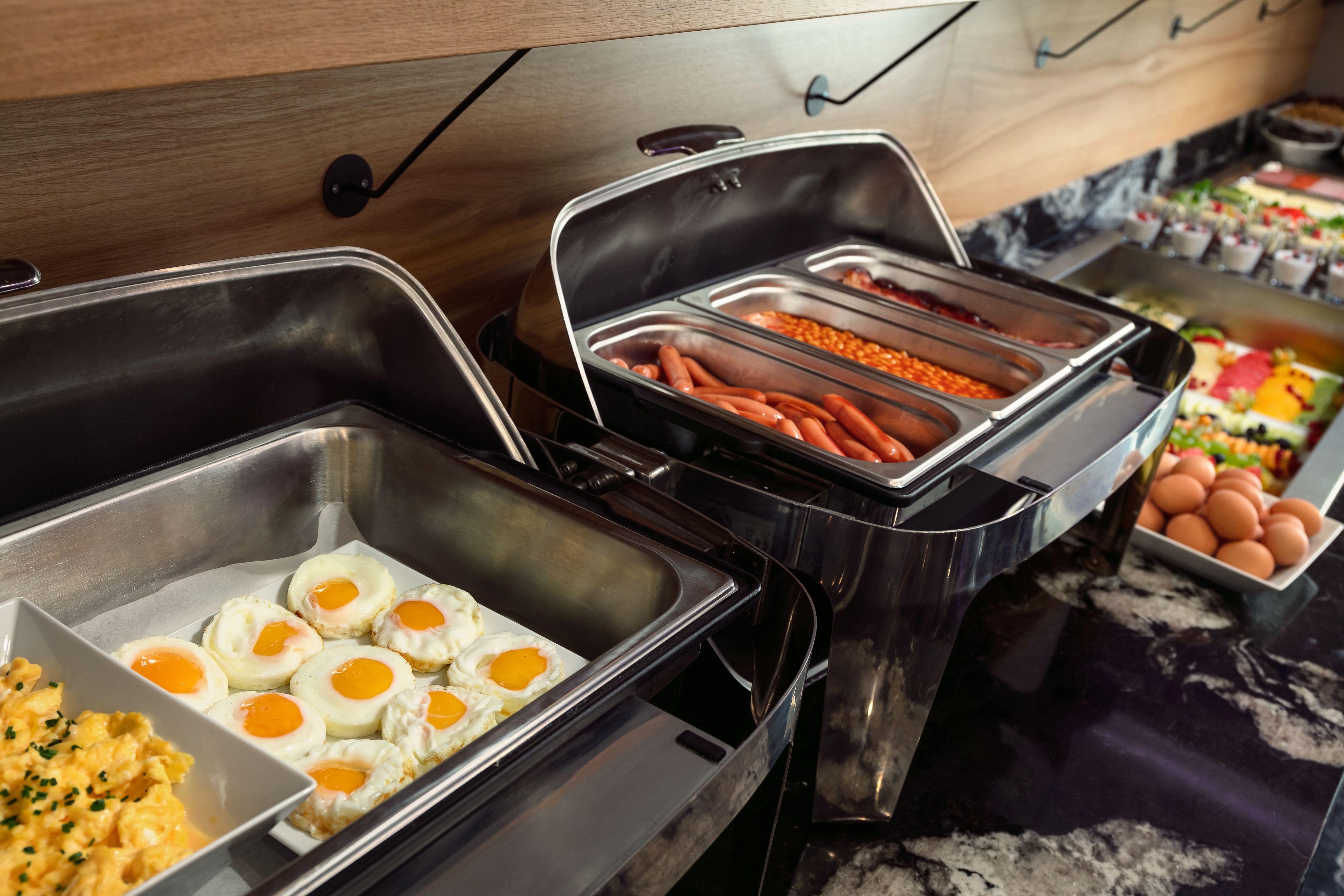 A buffet with various food options including eggs, macaroni, and vegetables.