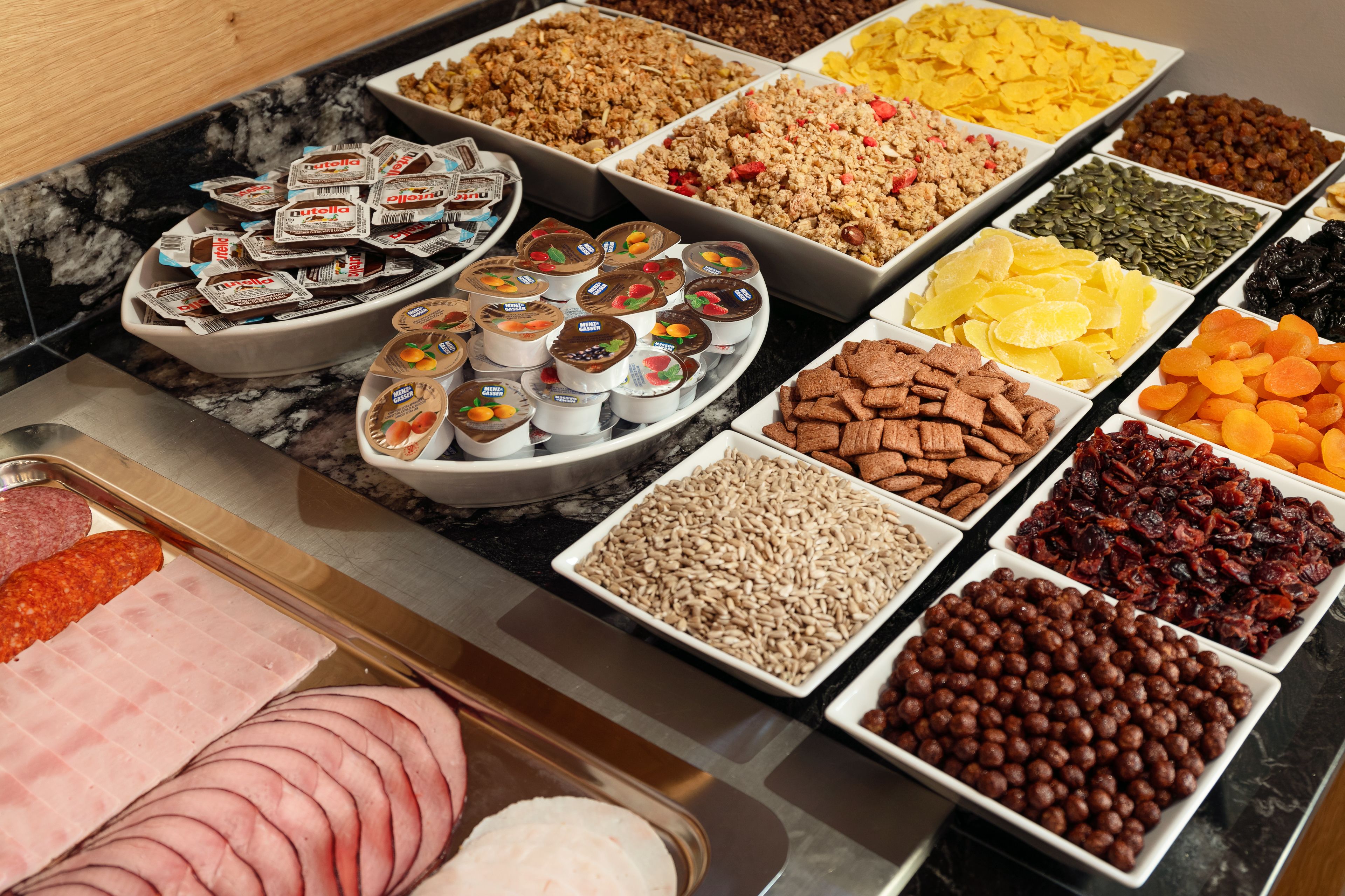 A buffet with various food items including meats, cheeses, and snacks.