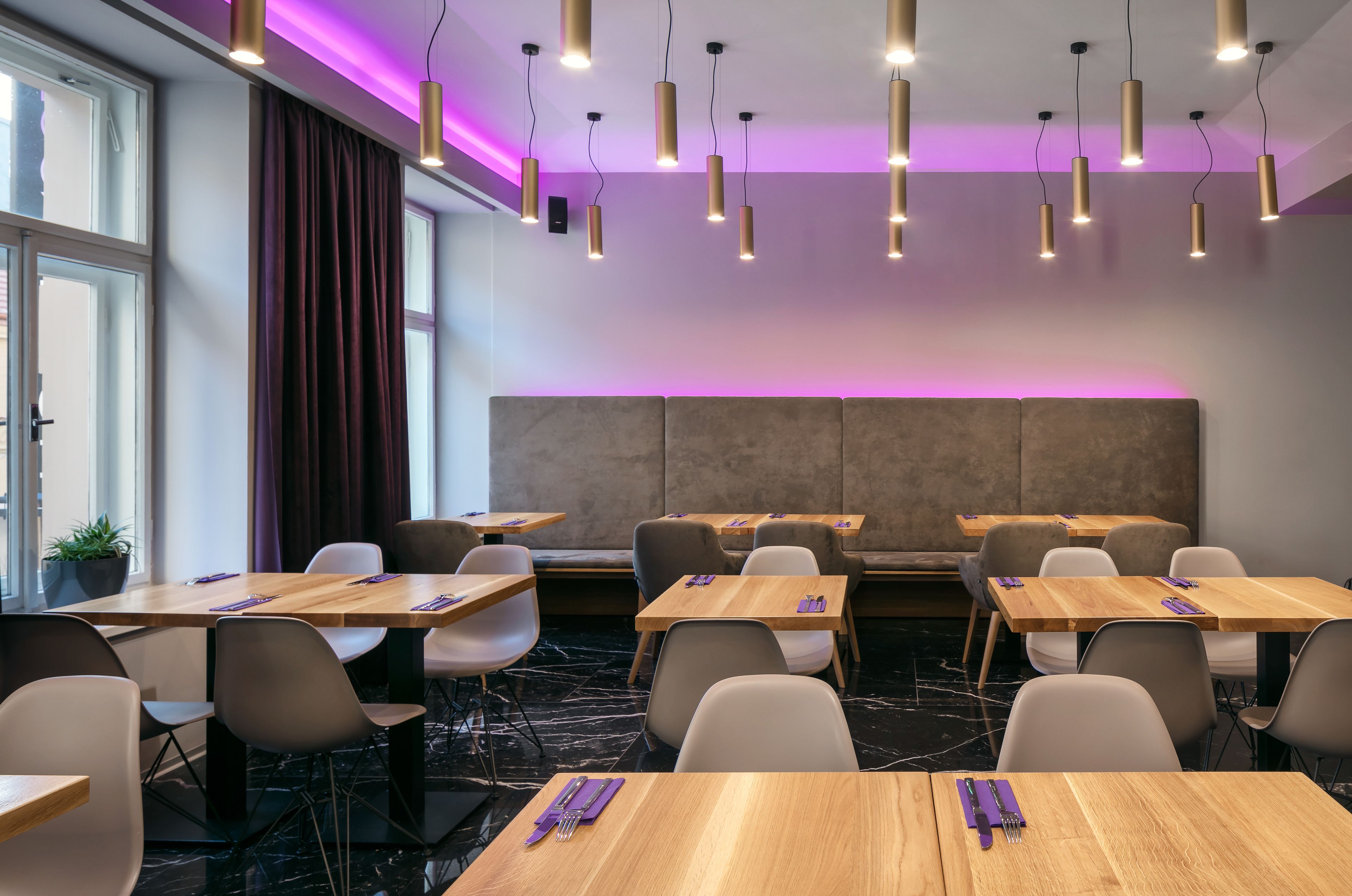 A modern conference room with wooden tables, white chairs, and a large cushioned seating area.