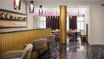 A modern bar area with a marble floor, bar stools, and a variety of bottles and glasses on shelves.