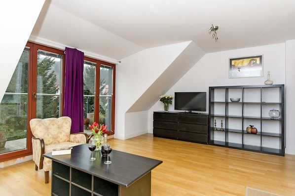 Una sala de estar moderna con un sofá, una mesa de centro, un televisor y una estantería.