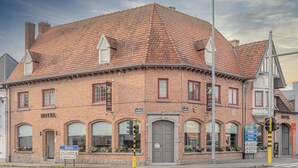 Un hotel històric amb teules vermelles, façana de maó i finestres d'arc.