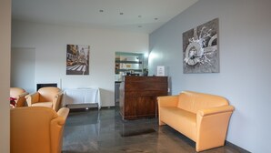 Un vestíbul modern amb taulell de recepció, dos sofàs i obra d'art a les parets.