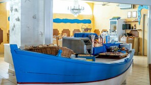 A boat-shaped buffet table with various food items and a chandelier in the background. - Hotel Giorgetti Orange (Bellaria-Igea Marina)