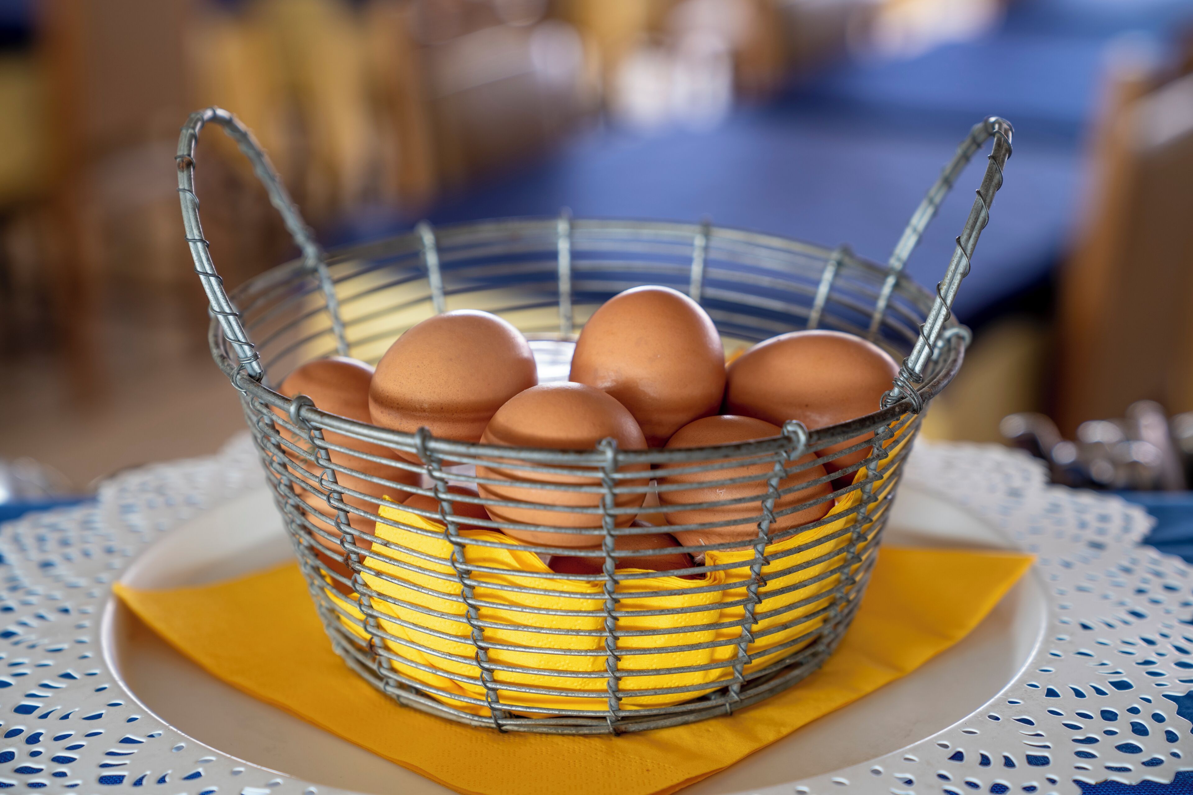 A metal basket with eggs on a table.