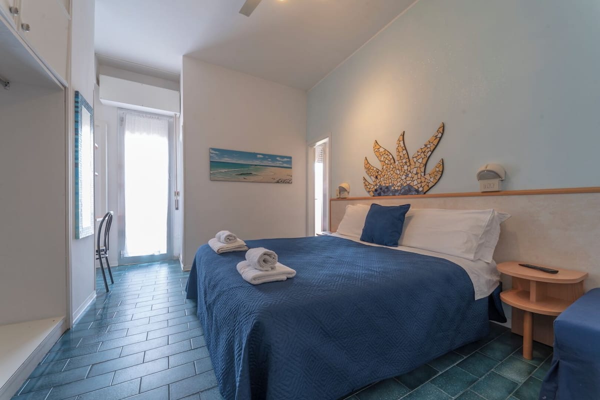 Una camera da letto con un letto grande, due asciugamani, un quadro e un elemento decorativo a parete.