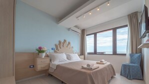 A hotel room with a bed, bedside table, lamp, window, and a view of the sea. - Hotel Giorgetti Orange (Bellaria-Igea Marina)