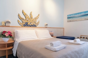 Une chambre d’hôtel avec un lit, un élément de décoration circulaire au mur, un tableau, une petite table avec un vase de fleurs et une chaise.