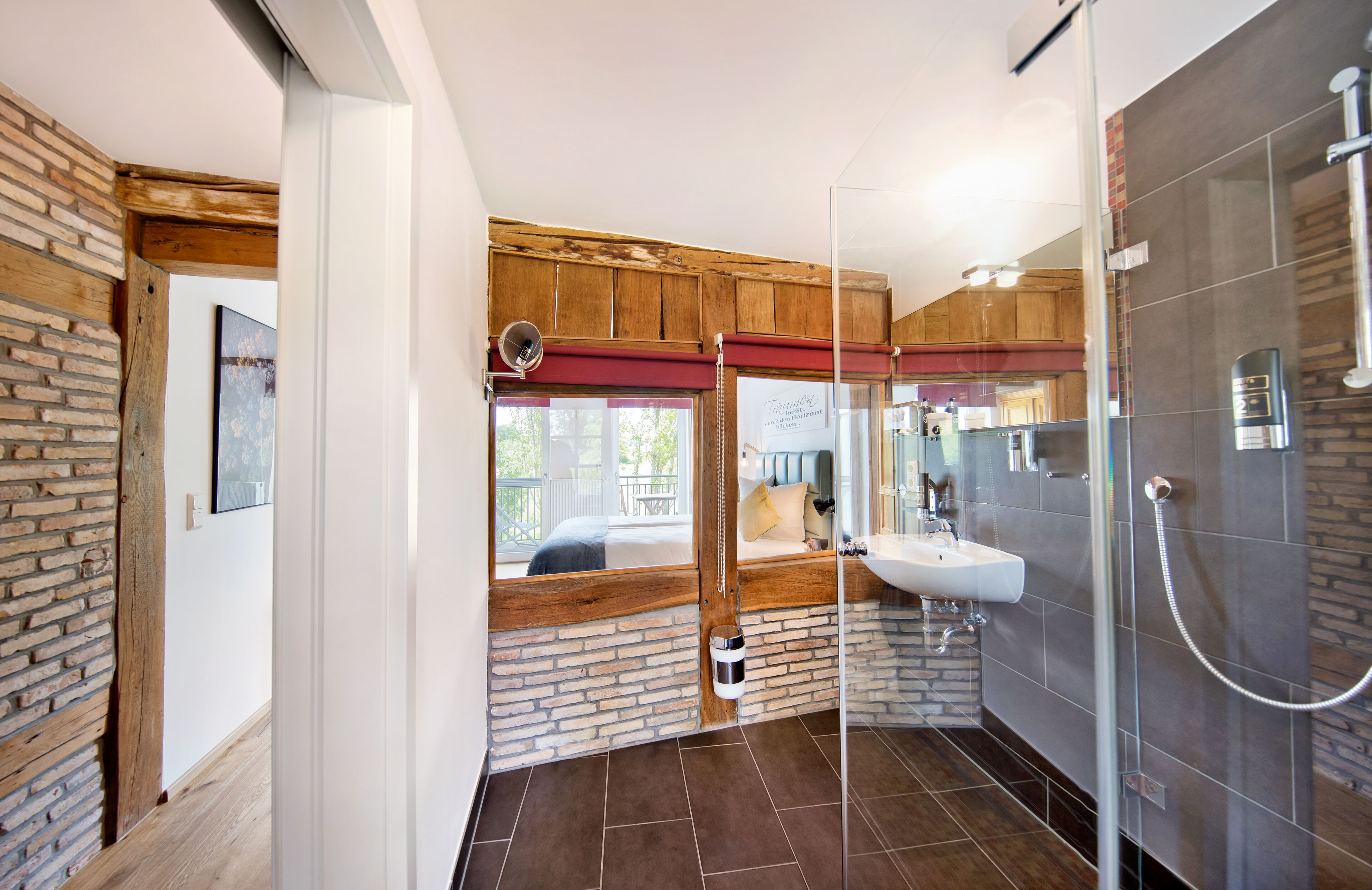 A modern bathroom with a glass shower enclosure, a wooden bench, and a view of the outside.