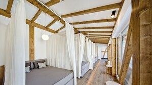 A room with a wooden ceiling, a bed with grey bedding, and a window with curtains. - Jordan's Untermühle (Koengernheim)