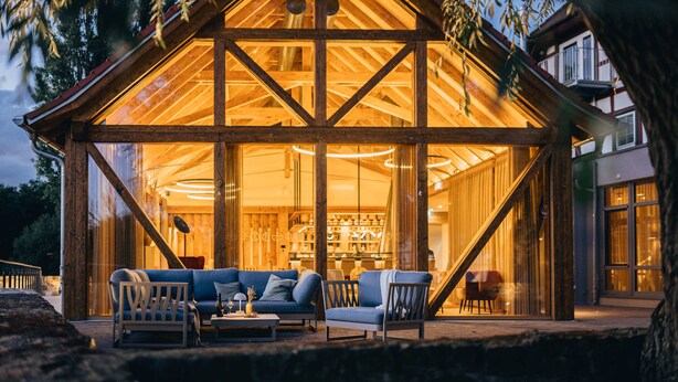 A wooden cabin with a glass facade, furnished with a sofa and chairs, and a staircase leading to the upper level. - Jordan's Untermühle (Koengernheim)