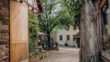 A cobblestone street leading to a white building with a wooden door and stone walls.