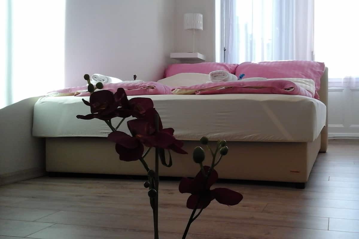 Une chambre à coucher avec un lit, une table de chevet et une plante en pot.